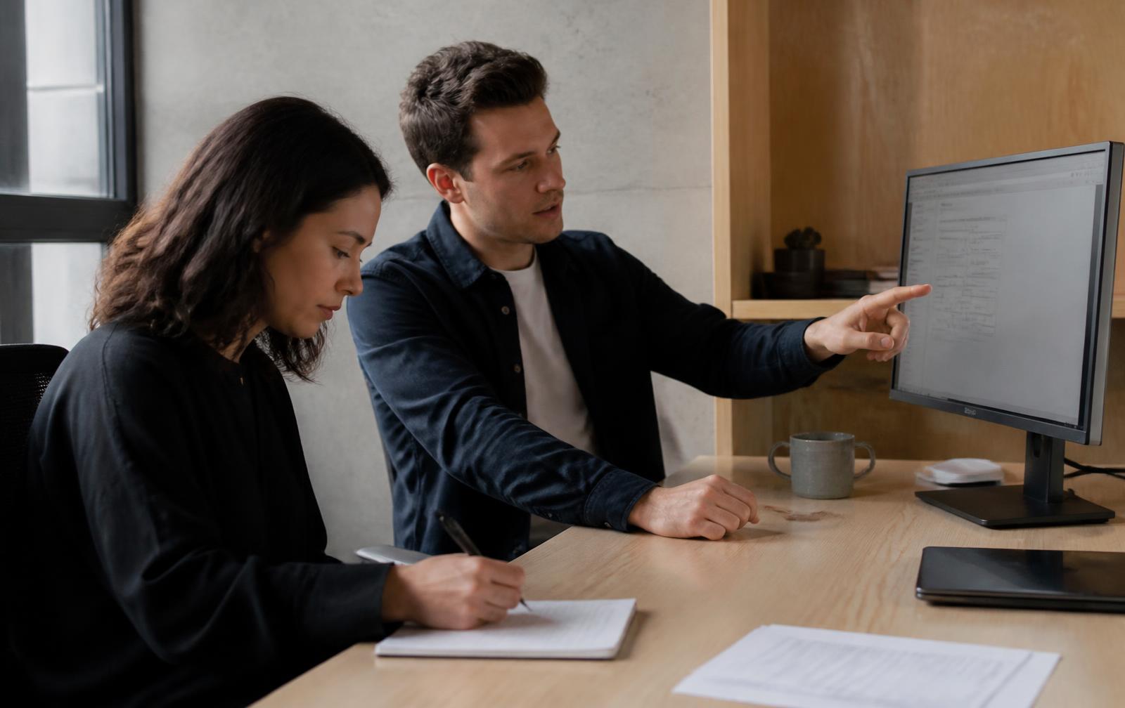 Two colleagues reviewing a process on screen during a hands-on training session